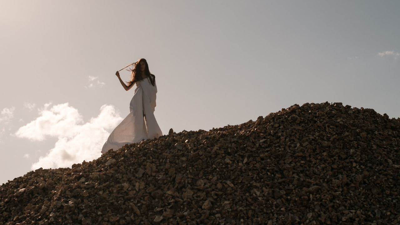 Chica caminando por la naturaleza con un vestido blanco disfrutando con la brisa del aire y sonriendo