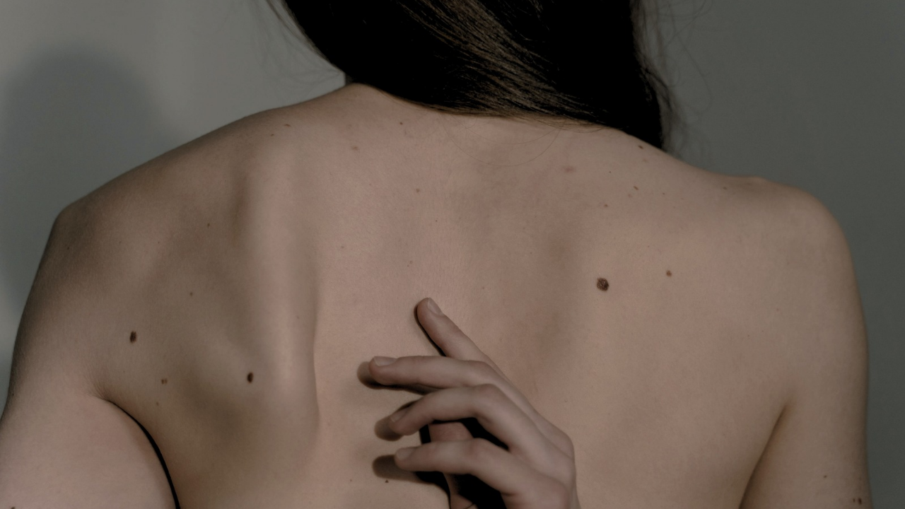 Espalda de mujer, acariciando su piel con delicadeza, con lunares y piel muy delicada