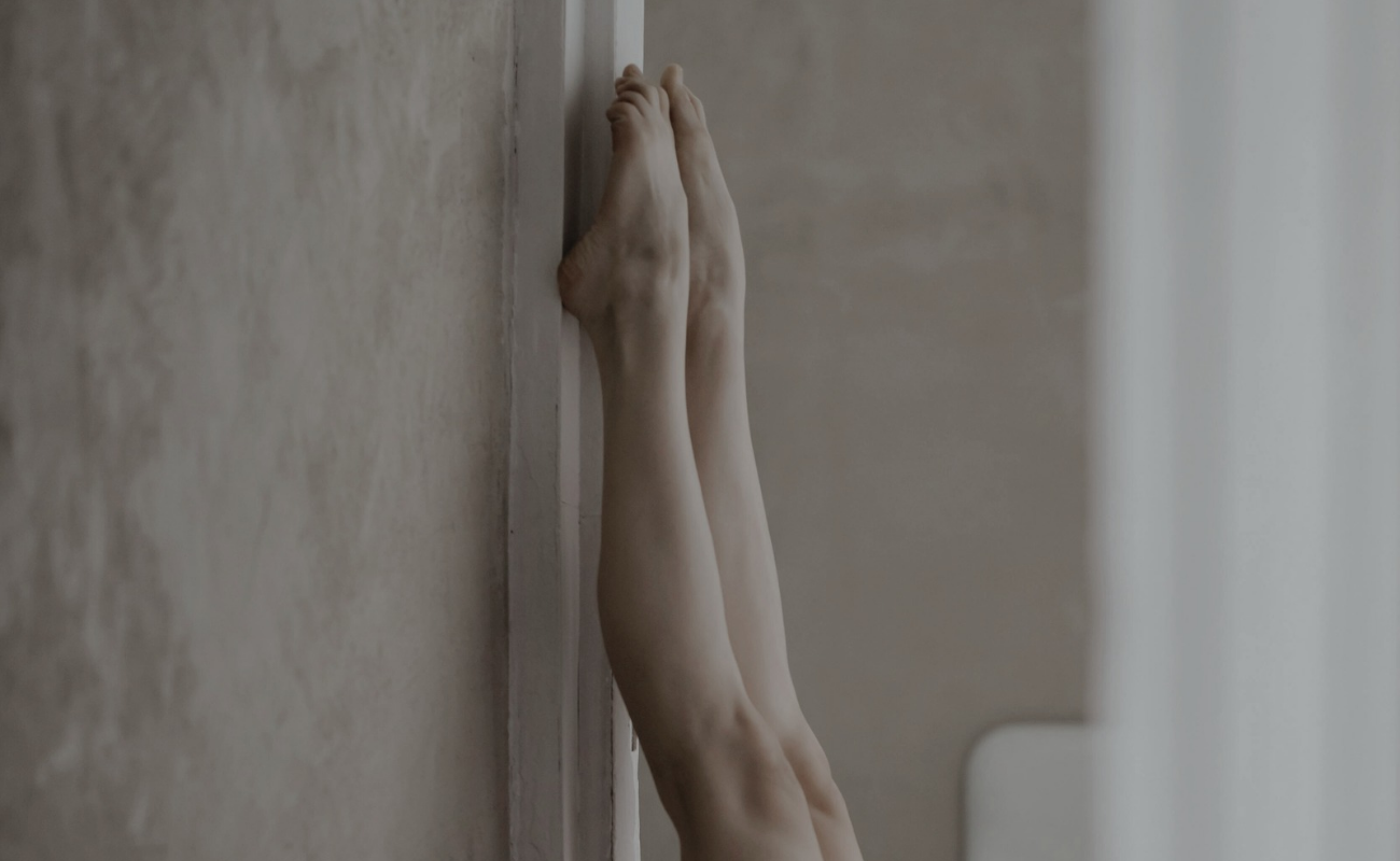 Piernas apoyadas en lo alto de la pared perpendicularmente con delicadeza y color claro con sensación de aterciopelado