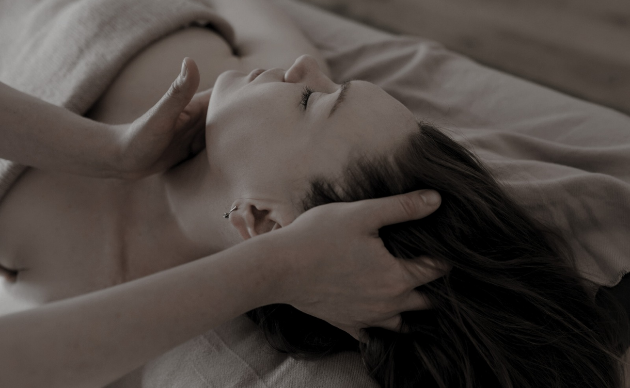 Manos d terapeuta de piel masajeando la cabeza y cuello de su paciente tumbada relajada joven y co rostro sereno y tranquilo